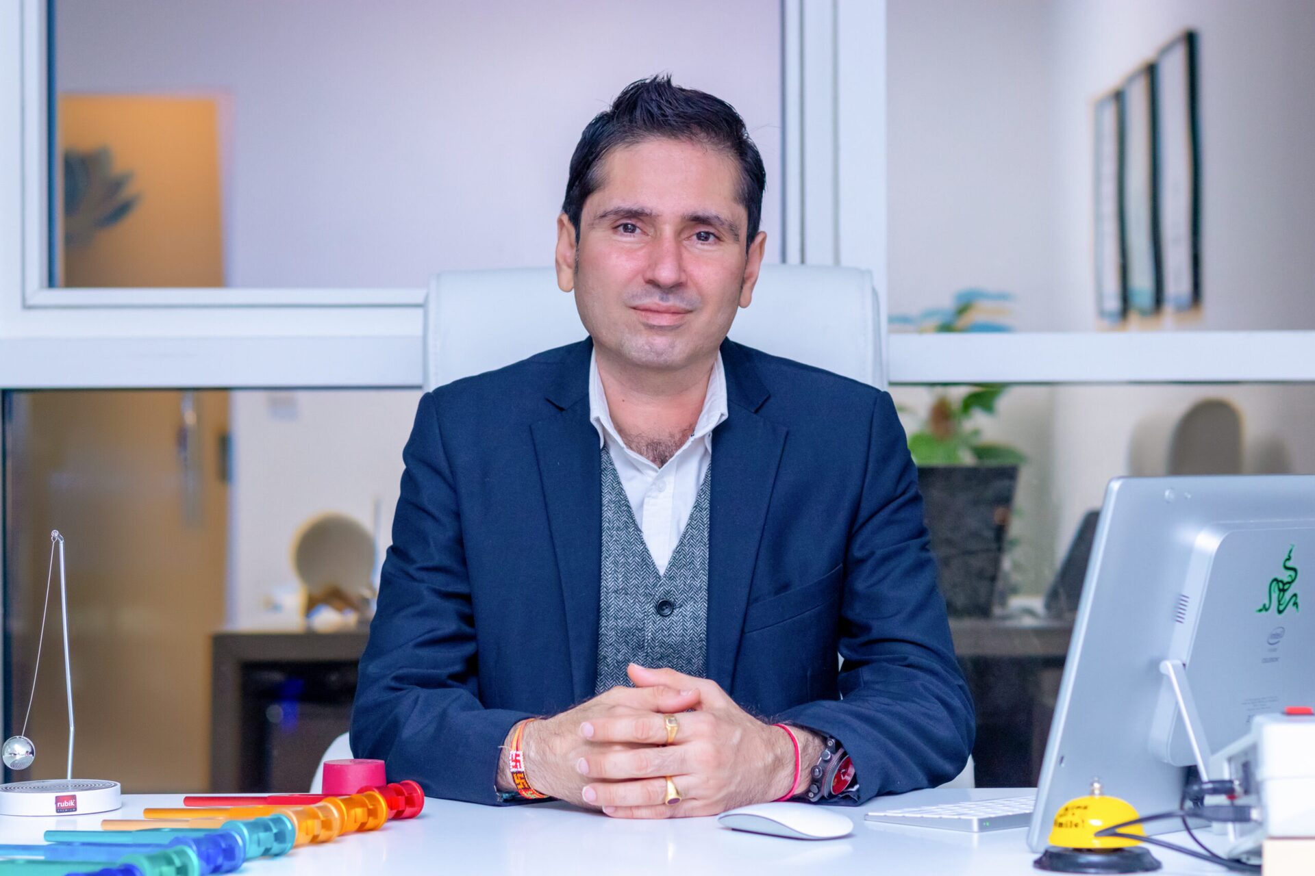 Yogesh Janak Gosain seated at his desk, hands folded, facing the camera